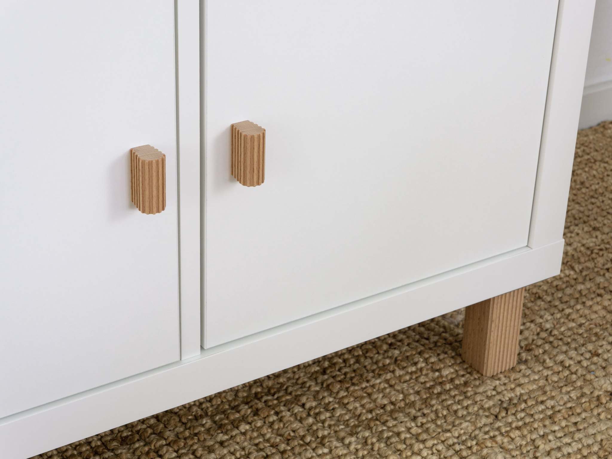 Witte IKEA Kallax-kast met houten knoppen op een gestructureerde vloer
