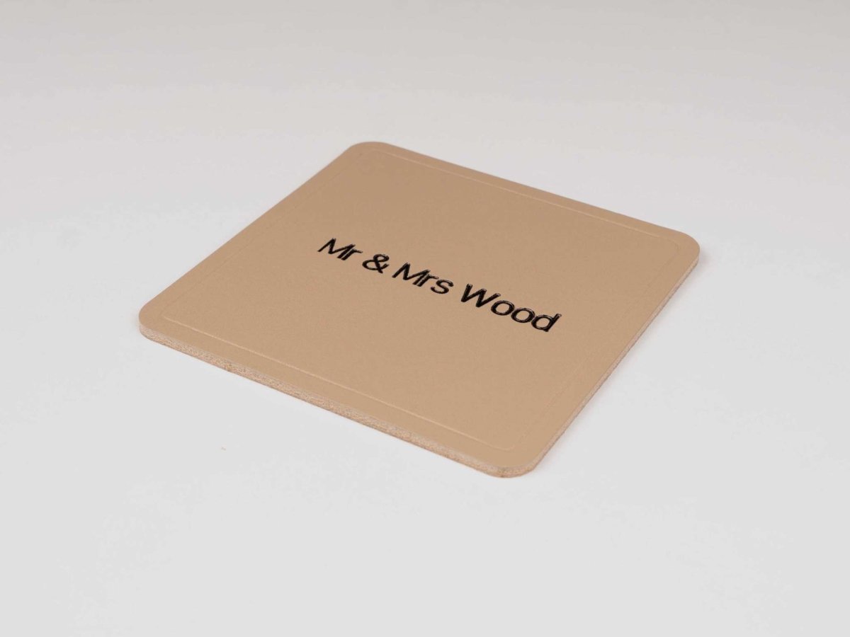 Personalized square leather coaster engraved with "Mr & Mrs Wood" on beige premium Italian leather