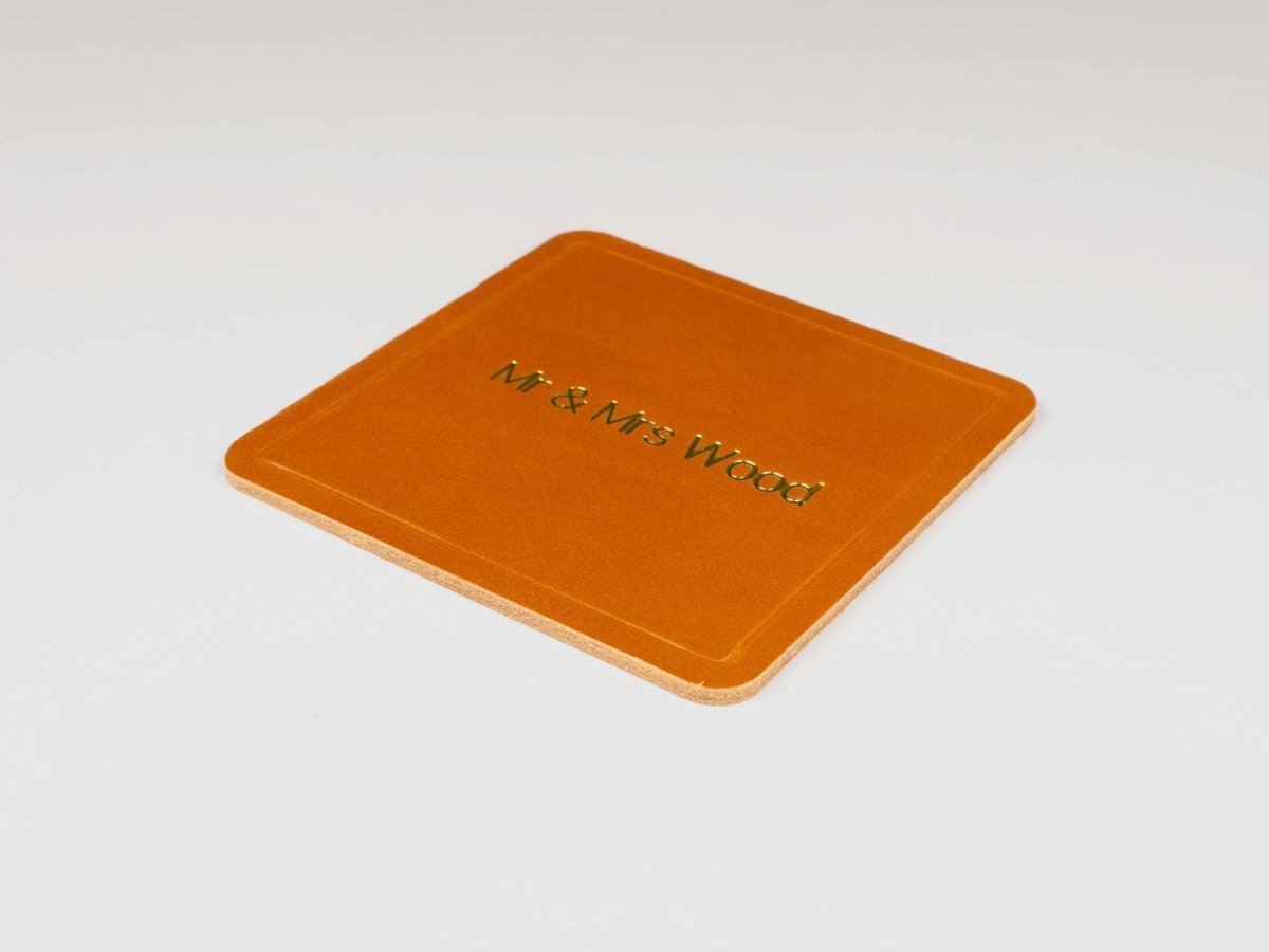 Personalized square leather coaster in premium Italian leather with custom foil-stamped text "Mr & Mrs Wood"