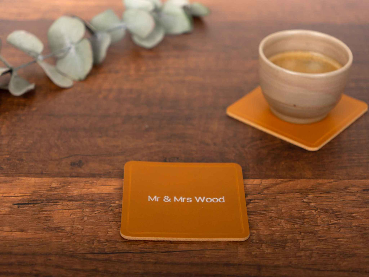 Personalized leather coaster square premium Italian leather with custom engraving on wooden table with coffee cup