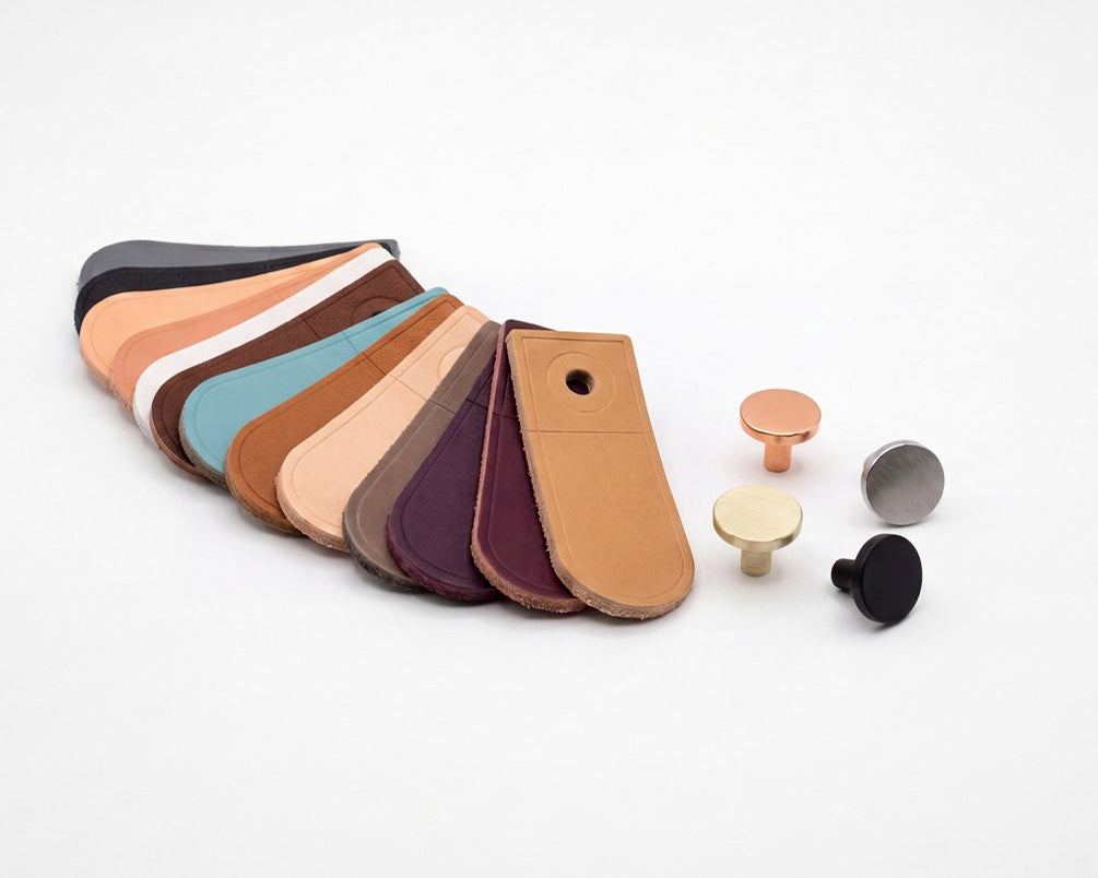 Leather samples in various colors and four metal knob samples in copper, gold, silver, and black finishes for Leather & Furniture Knobs.